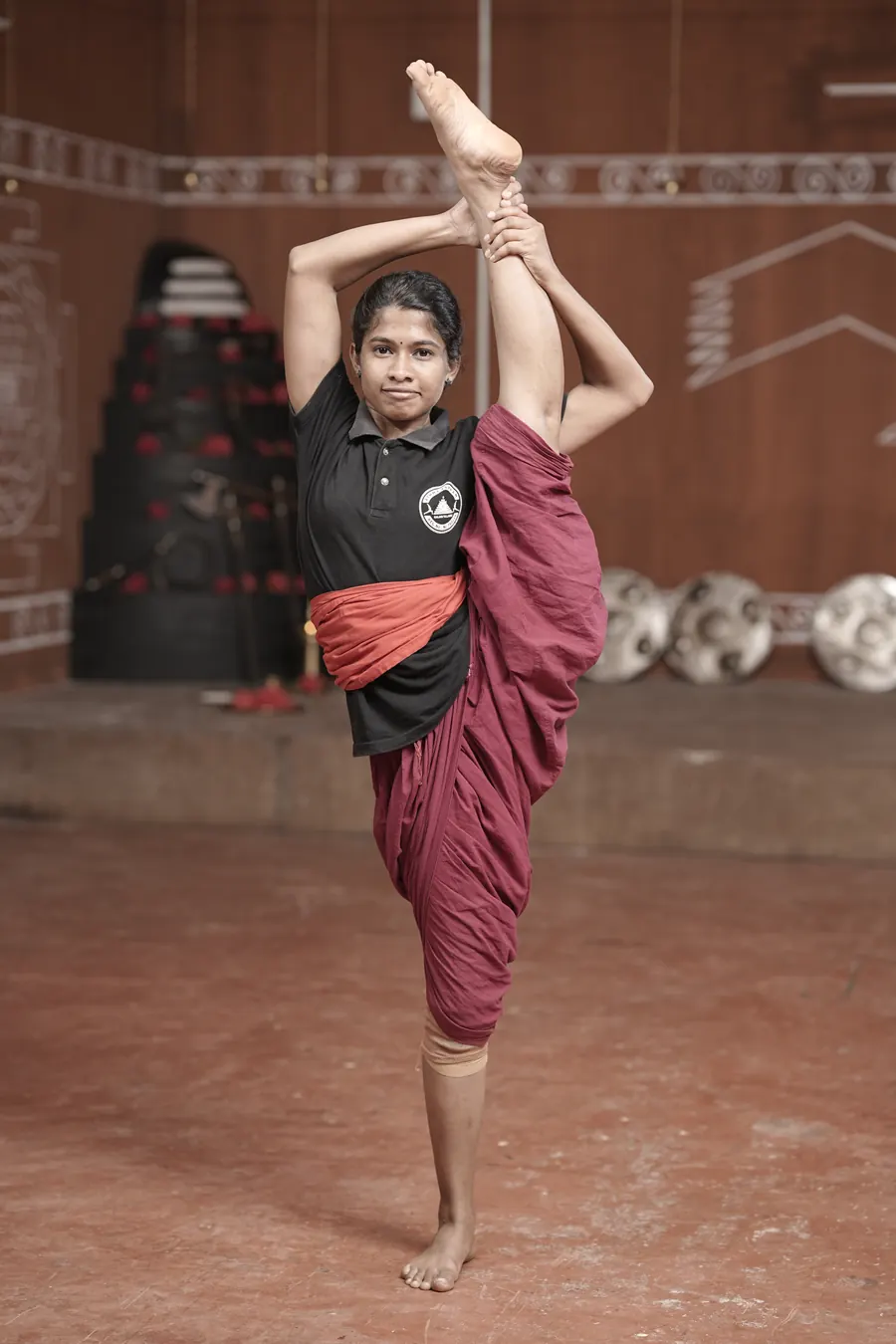 A Kalaripayattu student throwing a high kick in the kalari pit