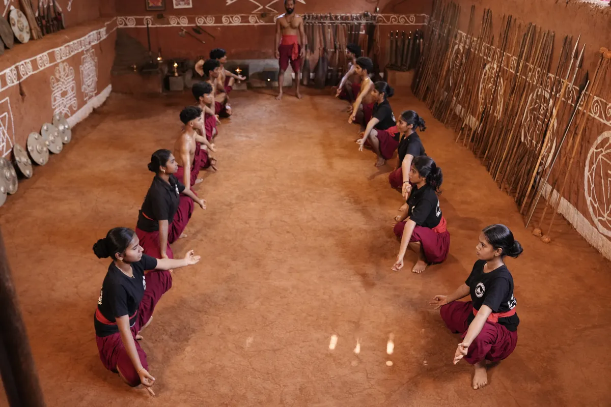 Students training in rows on the red earth floor of the kalari