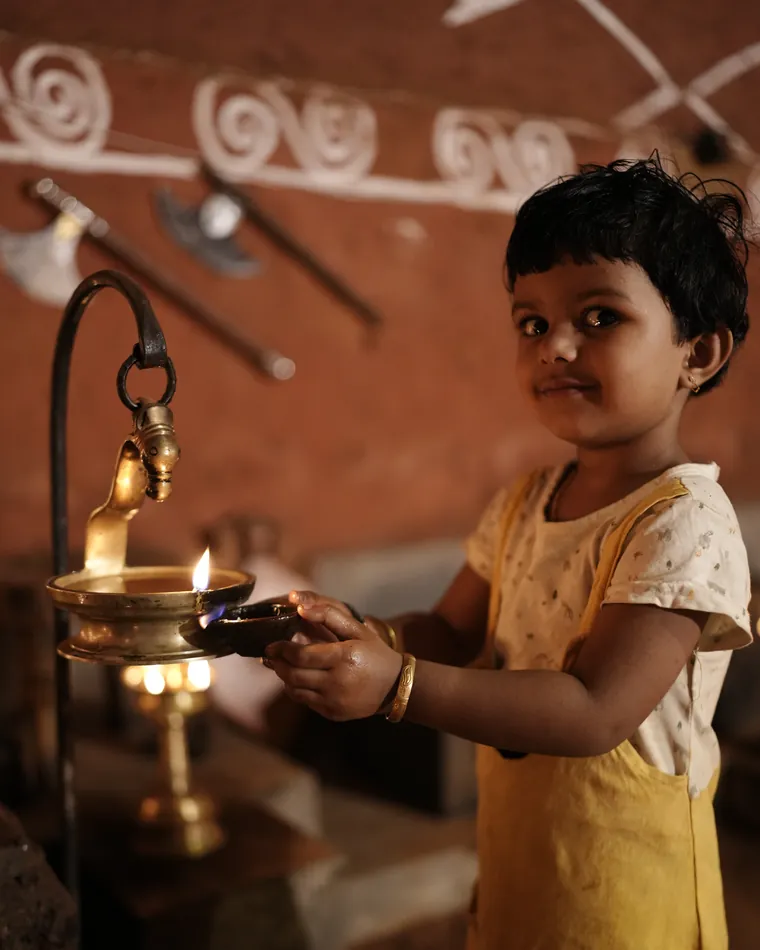 A child holding the lit brass lamp at dusk